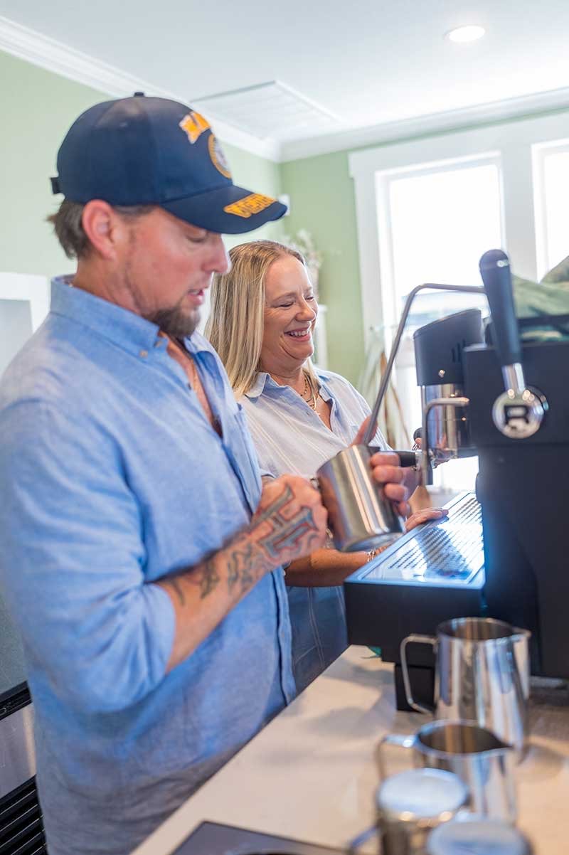 Owners Stephen and D'Ann Gimenez laughing while steaming milk at the espresso machine