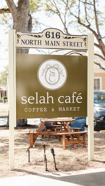 Selah Café sign with picnic tables under the oaks